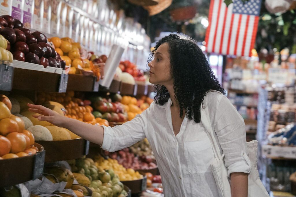 Woman picking an orange from a grocery store shelf