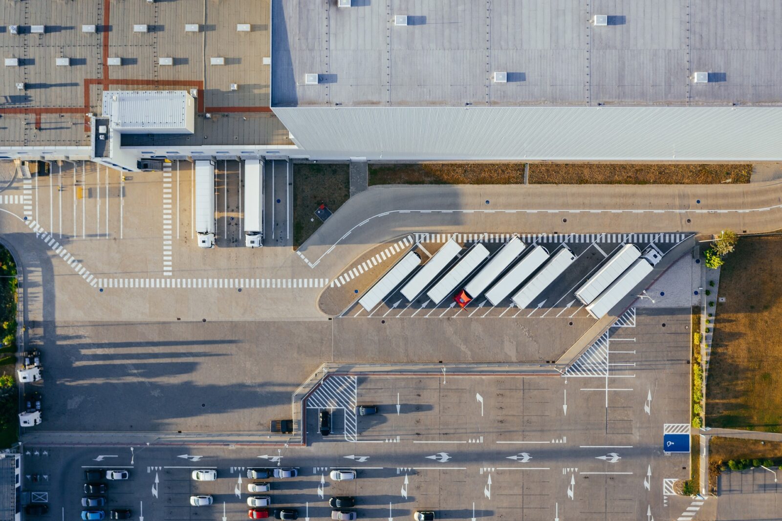 Overhead shot of the exterior of a warehouse facility with trucks parked in an adjacent parking lot