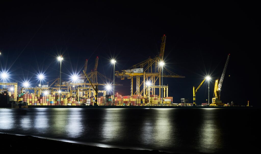 Picture of a sea port with cranes and shipping containers at night